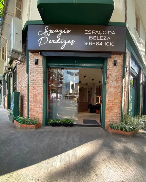 Entrada do Spazio Perdizes com porta de vidro aberta, vasos de plantas e letreiro com o telefone 9 6564-1010